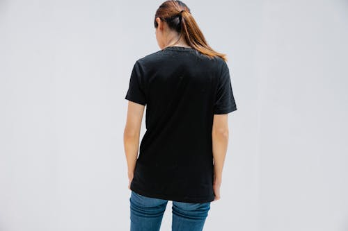 Back view of anonymous female in casual clothes with brown hair on light background