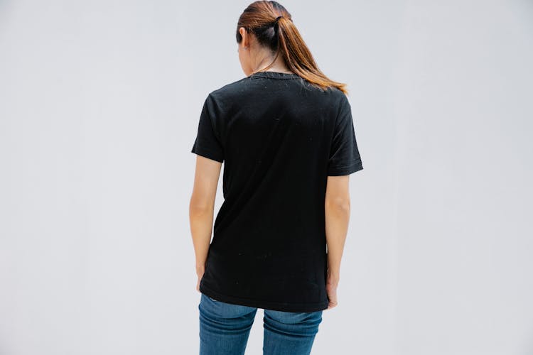 Unrecognizable Woman In Black T Shirt On Light Background