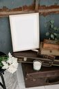 Empty photography frame on aged cases between wooden boxes and blooming Chrysanthemums against rough wall