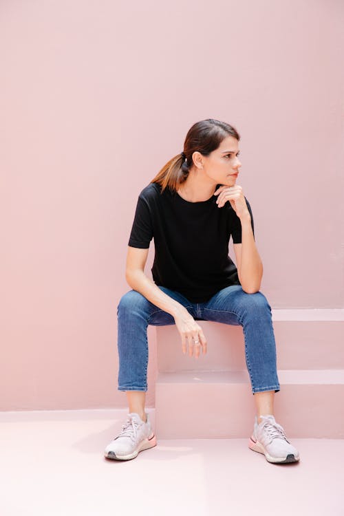 Free Thoughtful model in sneakers resting on staircase Stock Photo