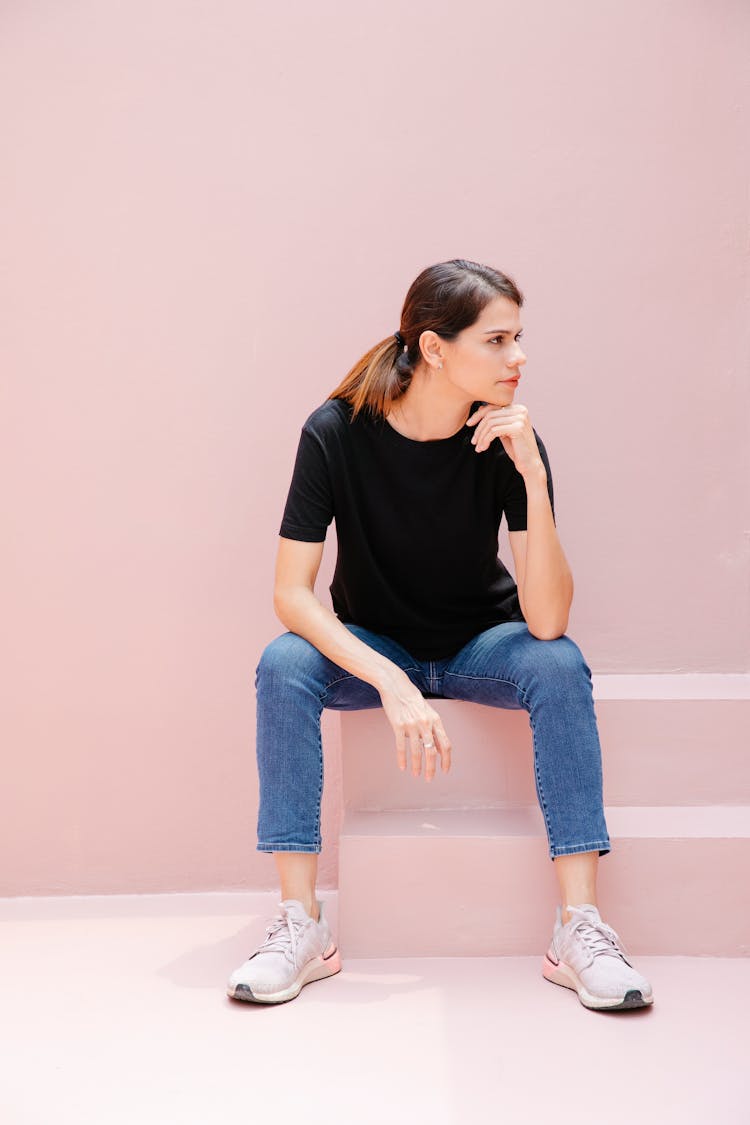 Thoughtful Model In Sneakers Resting On Staircase