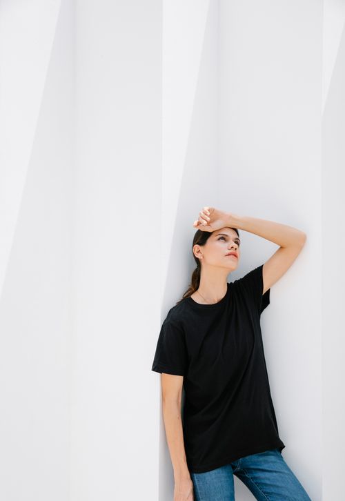 Free Young contemplative woman in casual clothes looking up against ribbed wall on sunny day outdoors Stock Photo