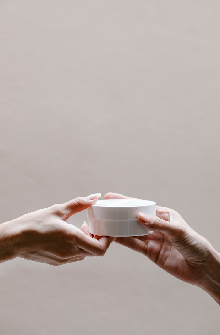 Crop Woman Passing Jar Of Moisturizing Cream To Partner