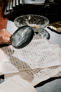 A close-up of a detective analyzing cryptic documents with a magnifying glass.