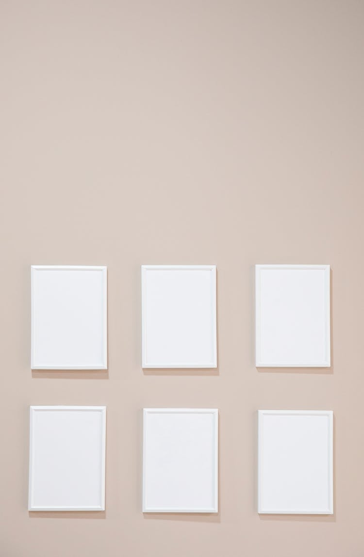 Empty White Photo Frames Hanging On Gray Wall