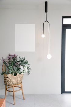 Bouquet of fresh wildflowers in wicker basket placed near wall with white mockup