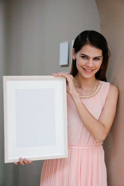 Graceful lady demonstrating frame mockup and smiling at camera