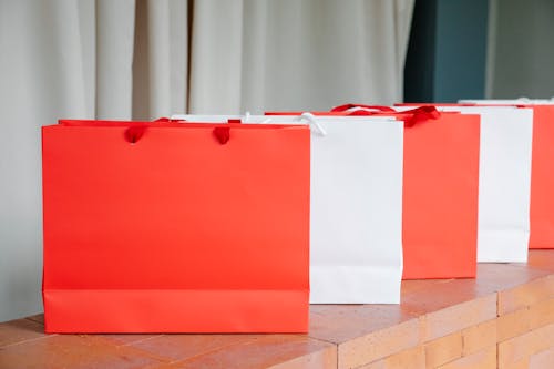Set of red and white paper shopping bags placed on brick shelf in studio