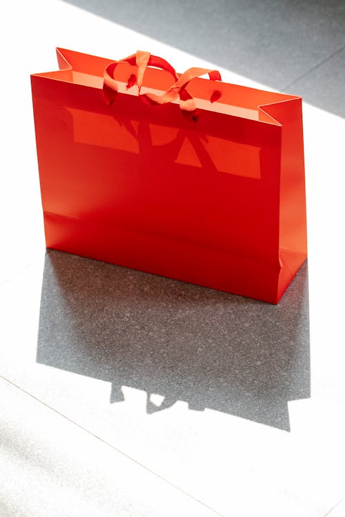 Red shopping bag placed on street in daylight