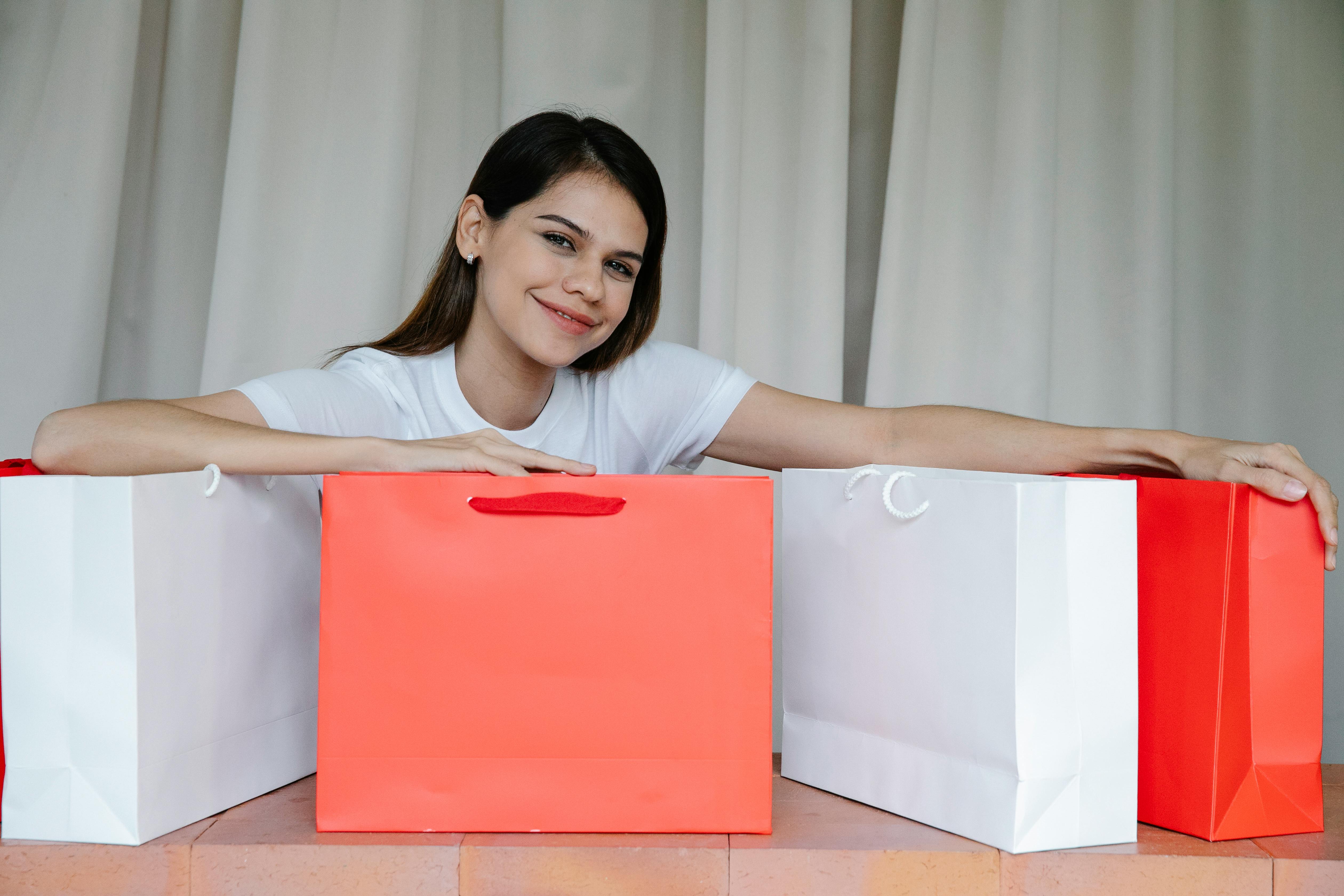 delighted young woman showing purchases in paper bags and smiling