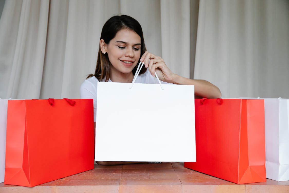 Free Happy young woman putting shopping bags on table after delivering purchases Stock Photo