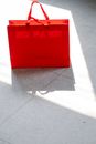 From above of red paper bag placed on tiled ground on street after shopping on sunny day