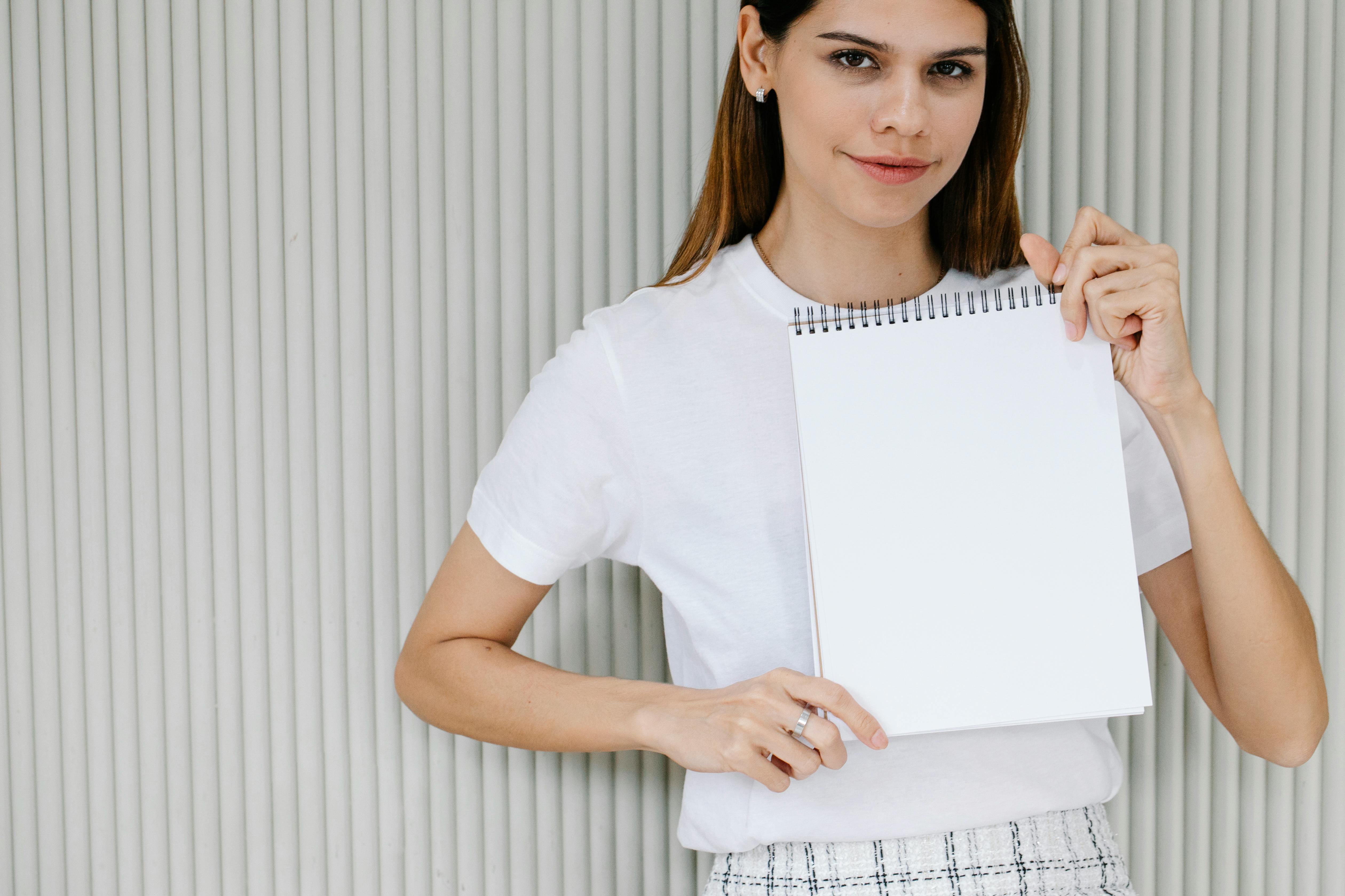 young lady showing planner with white sheet and looking at camera