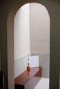 Wooden bench with vase of gentle flower and white paper placed on terrace near archway