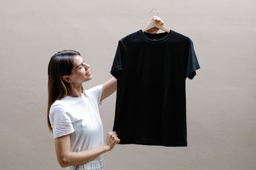 Free Smiling young woman showing casual t shirt against gray wall Stock Photo
