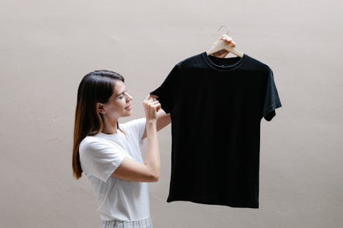 Side view of positive female wearing casual outfit standing with black shirt against gray background