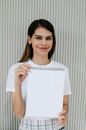 Smiling woman showing empty notebook against striped wall
