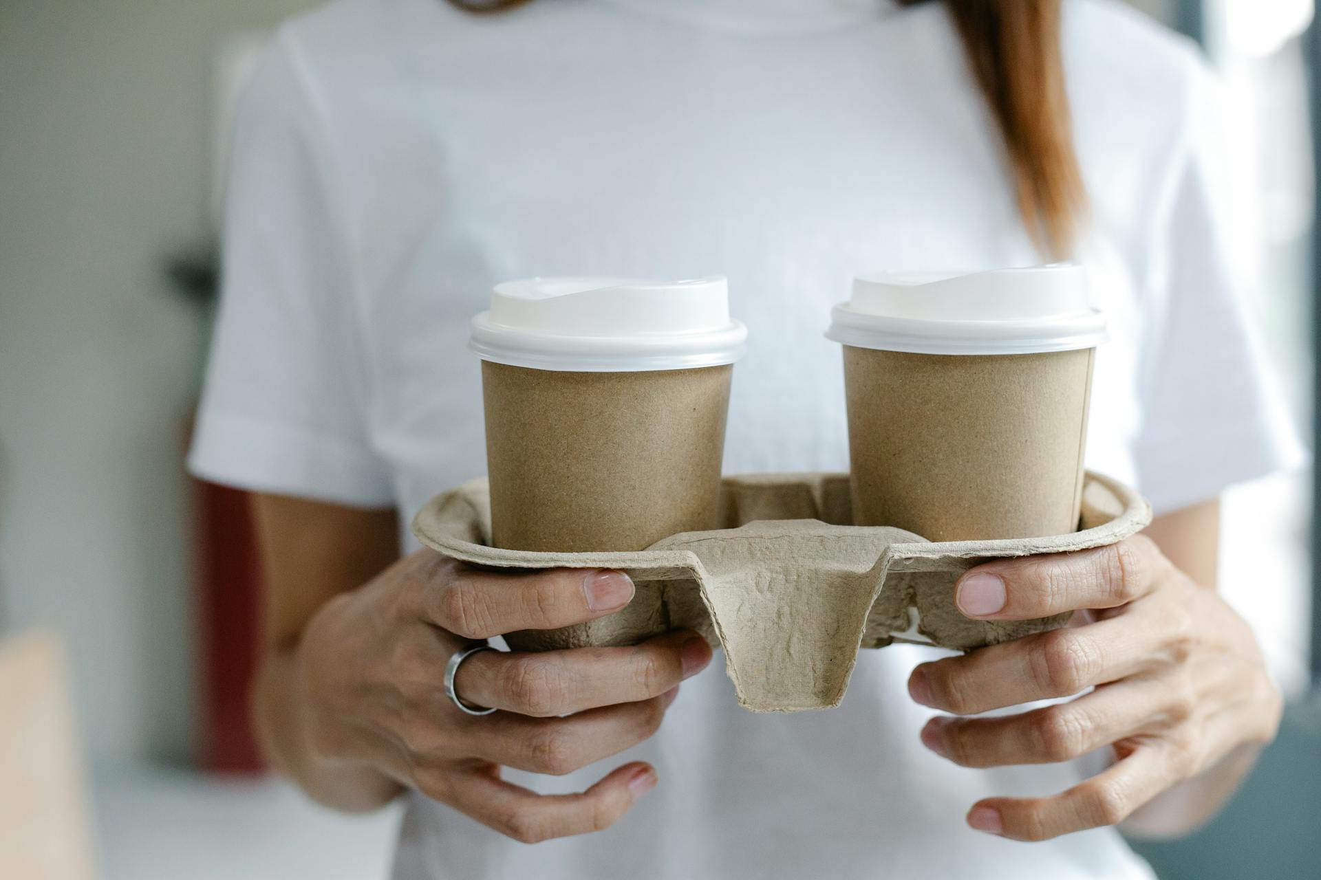 Crop woman with coffee to go