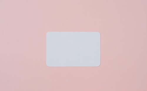 White visiting card with empty space for data placed on light pink background