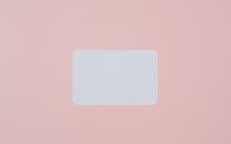 White visiting card with empty space for data placed on light pink background