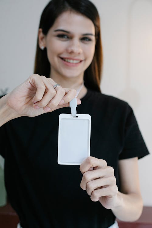 Free Glad young woman smiling for camera and showing empty name tag during seminar Stock Photo
