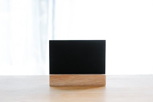 Empty black name card on wooden holder placed on desk in modern workplace