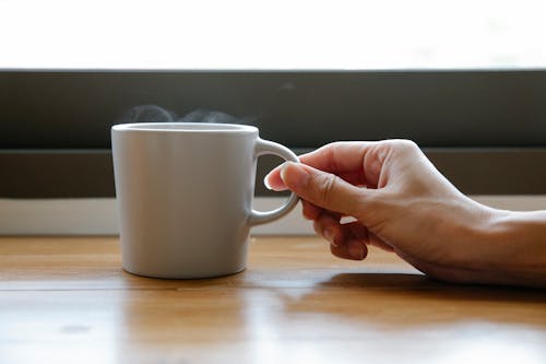 Free Crop faceless woman touching cup of aromatic hot drink Stock Photo