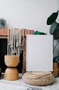 Composition of empty white photo frame placed near brick fireplace and cozy decorations in light room