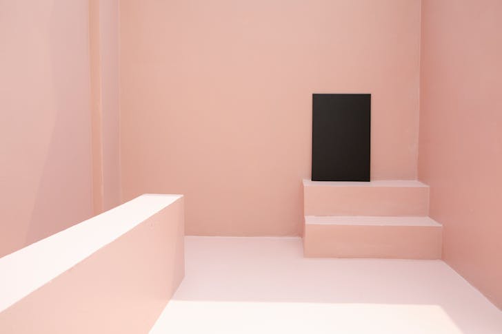 Black canvas placed on staircase in pink room