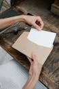 Crop unrecognizable woman placing blank paper in envelope