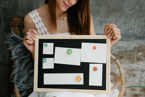 Free Smiling woman showing noticeboard with blank papers Stock Photo