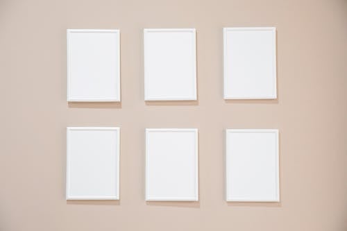 Free Rows of blank white rectangular frames hanging on light pink wall in studio Stock Photo