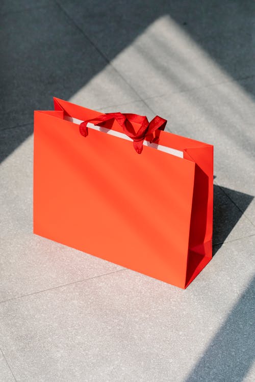Free High angle of bright paper present bag with handles placed on tiled floor at sunlight Stock Photo