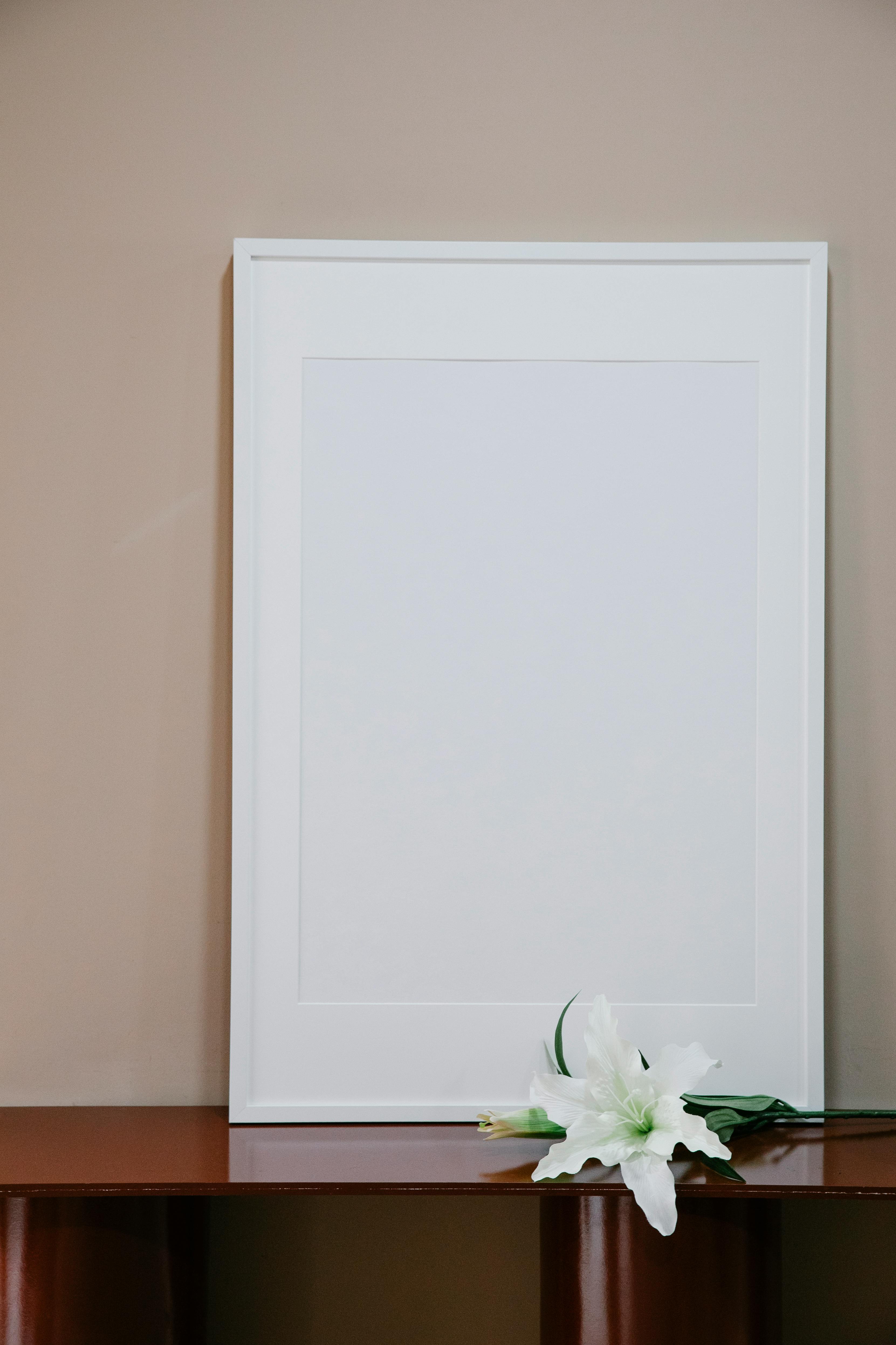 blank frame placed on glossy table near flower