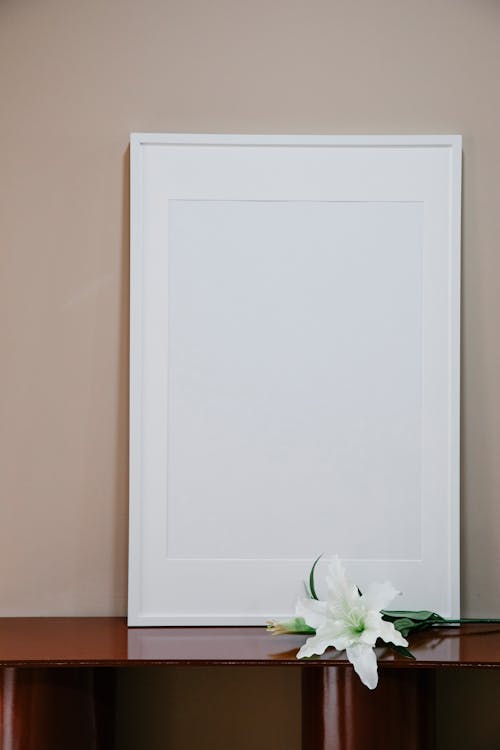 Free Empty photo frame placed on wooden shelf near branch of blooming fragrant flower Stock Photo