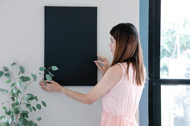 Woman Hanging Black Frame On Wall