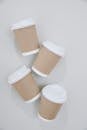 From above of paper cups for takeaway coffee with plastic lids placed on white background