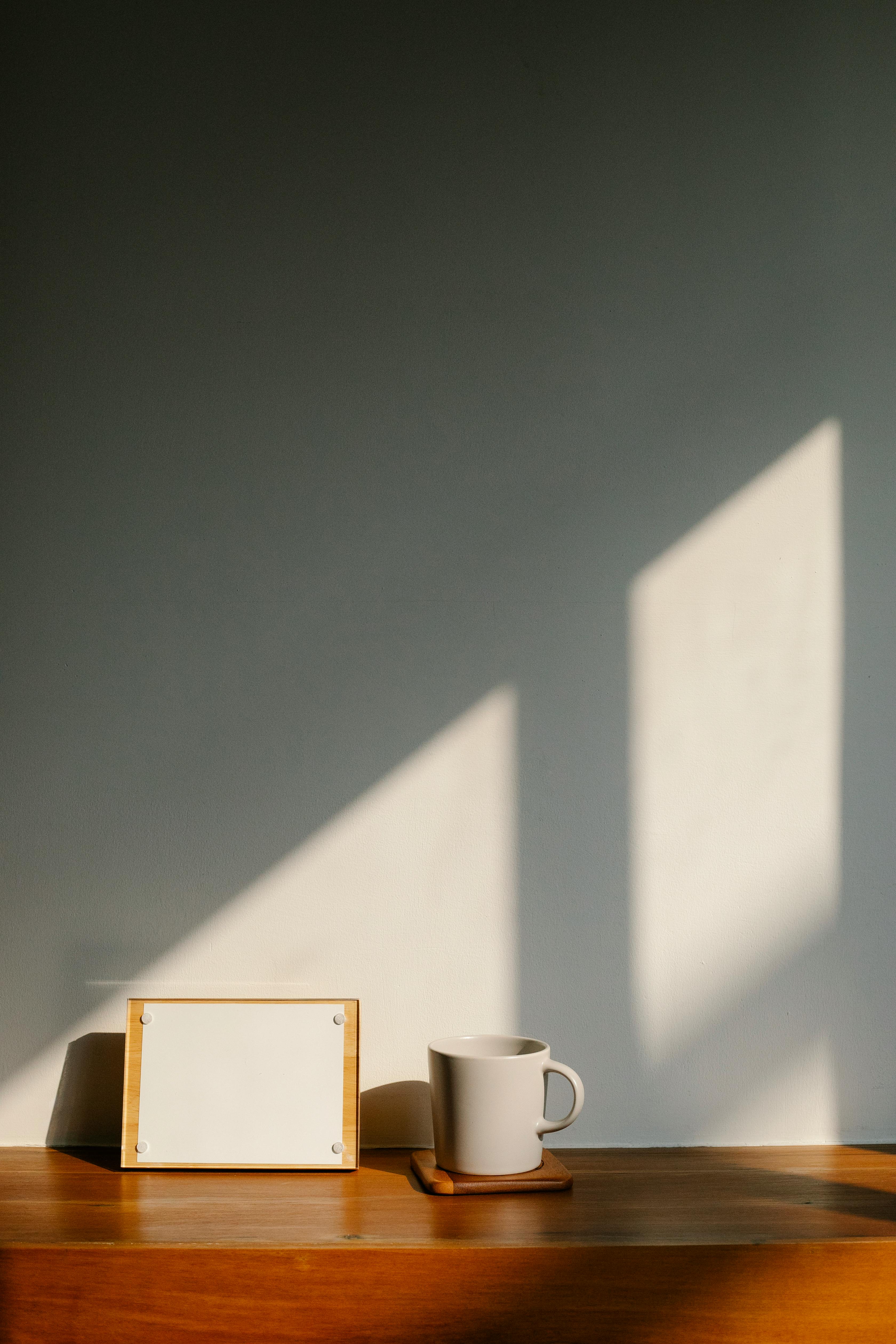blank picture frame and cup on wooden table