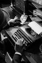 Monochrome Photo of Person Using Vintage Typewriter