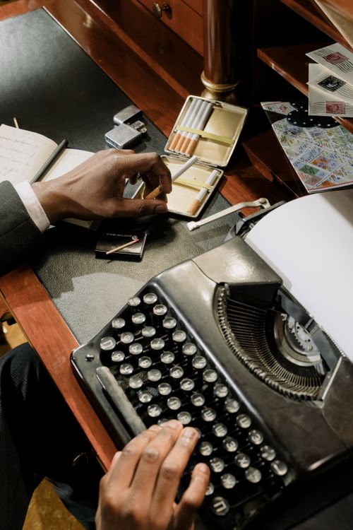 Free A vintage-styled photo depicting a businessman working on a typewriter in a classic office setting. Stock Photo
