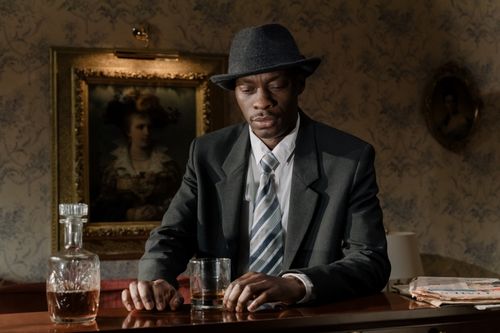Free A 1950s detective ponders over a whiskey drink, evoking a classic noir atmosphere. Stock Photo