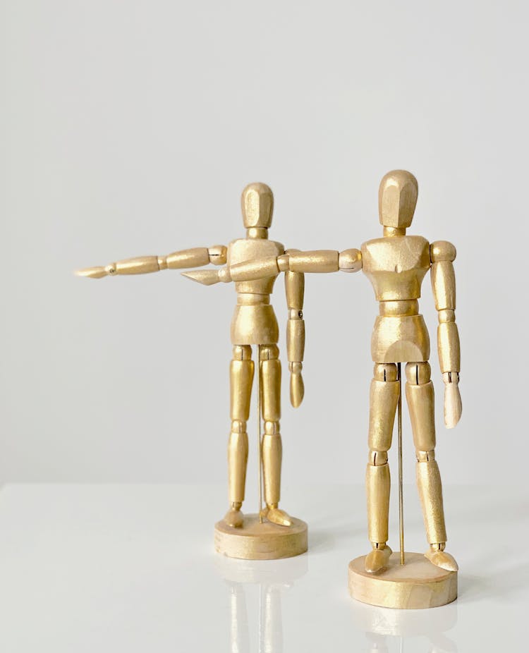 A Pair Of Gold Human Figurines With A Round Stand