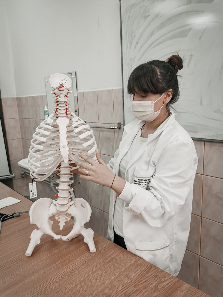 Woman Wearing Face Mask Touching The Rib Of The Skeleton