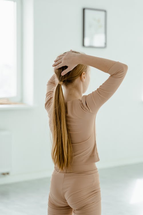 Back View Shot of a Girl with Long Hair Touching Her Head