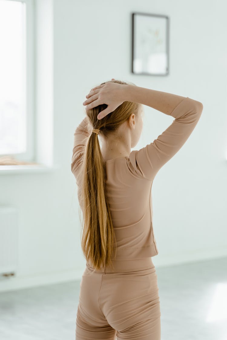 Back View Shot Of A Girl With Long Hair Touching Her Head