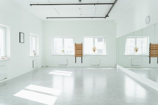 Bright and empty dance studio with mirrors and sunlight streaming in.