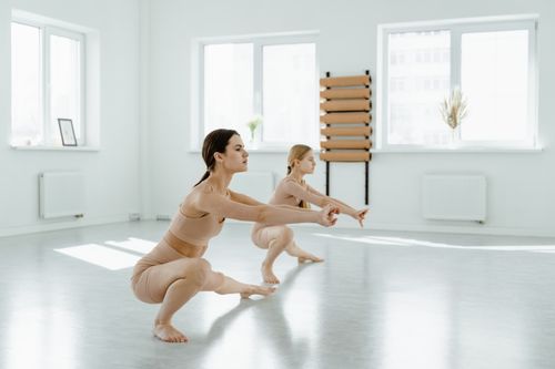 Free Two women performing ballet stretches in an airy, sunlit dance studio. Stock Photo