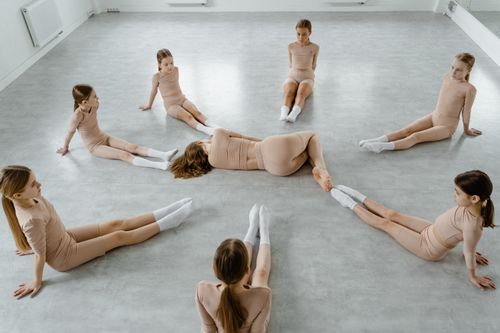 Free Aerial view of girls in light outfits practicing dance positions inside a studio. Stock Photo
