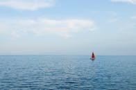 一艘红帆孤舟在晴空下平静地航行于公海