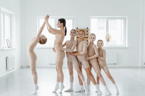 Free Group of young ballet dancers in nude leotards practicing together in a bright dance studio. Stock Photo